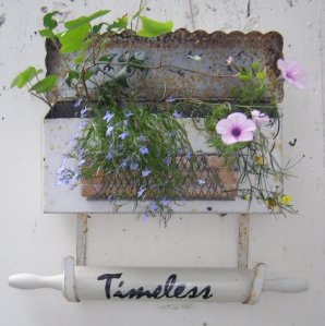 a mailbox rescued from a nearby teardown makes a pretty and whimsical planter. A bricklayer's tool added to the front for texture and a vintage rolling pin for signage.