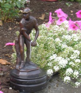 There is something very appealing about the contrast between the hard dark bronze figurine and the fluffy light flowers of alyssum and petunias